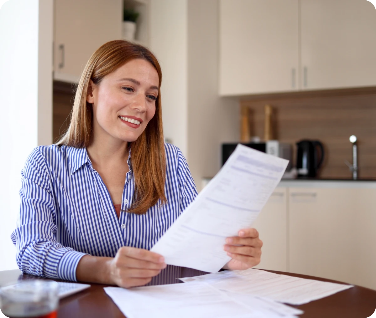Woman holding papers, smiling at table